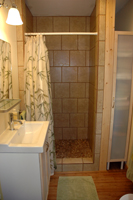 A comfortable bath with a pebbled floor in the shower.